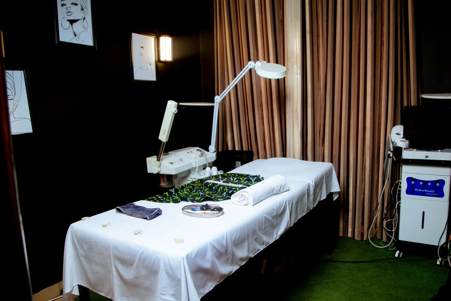 Facial treatment room with a dressed bed, magnifying lamp and skincare machines