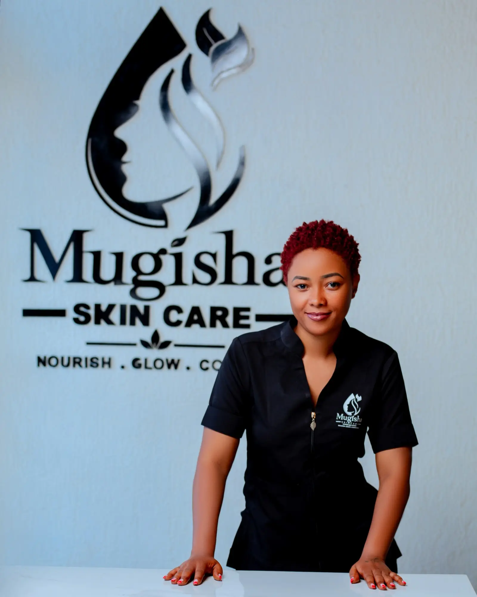 Team member at the reception desk beneath the Mugisha Skin Care logo